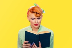 Girl with book. Closeup red head beautiful young woman sad unhappy reading pinup girl green button shirt isolated yellow background wall. retro vintage 50's hairstyle. drama tragic negative emotion