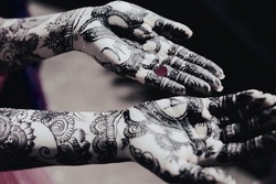 Henna tatooed hands of a bride and a little red heart