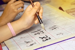 Asian students practice the art of Chinese calligraphy by writing Chinese characters, the word 
