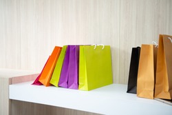 Colorful paper shopping bags on the shelf at home