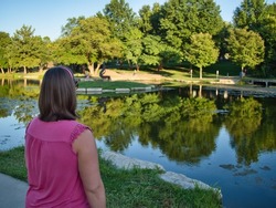 Brunette standing by the reflective waters of Sar Ko Par Park in Lenexa Kansas