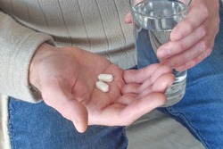 Man holding pills and a glass of water.  Healthcare and medical concept.