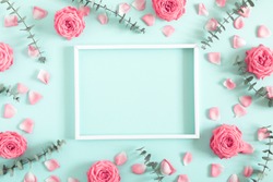 Beautiful flowers composition. Blank frame for text, pink rose flowers,  eucalyptus leaves on pastel mint background. Valentines Day, Easter, Birthday, Mother's day. Flat lay, top view, copy space