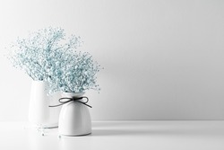 Elegant floral soft white composition, white flowers. Beautiful white gypsophila flower in vase on white wall background.