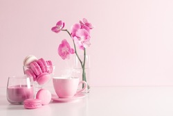 Beautiful flowers composition with pink orchid flower, steaming cup coffee or hot drink and macaroon on pastel pink background. Valentine's day, Happy women's day