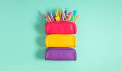 Back to school concept. Bright school pencil case with filling school stationery, pens, pencils, scissors, rule. School accessories on blue background. Flat lay, top view, copy space