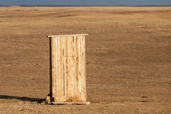 Photograph of an old rural outhouse or toilet in steppe. Single wooden building.