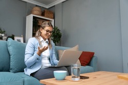 Young businesswoman sitting at home having video call with clients in formal wear while down in a tracksuit. Web conference on laptop computer of CEO female.