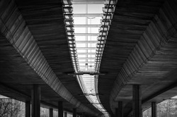 Architecture lines under the bridge with concrete poles and reinforcement protecting the bridge from collapsing black and white, transportation industry concept