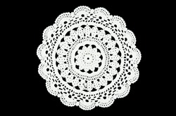 White hand made crocheted coaster lace doily on black background. 