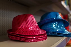 Pink and blue shiny hats with sequins for party or holiday celebration. Birthday accessories on supermarket shelf