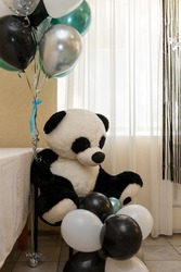 Big panda bear cuddly toy. Black, white, green and silver helium balloons for baby boy birthday party. 1 year old