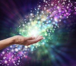 Magical Energy Healing Hands Concept - sparkling and bokeh background with a female open palm in the middle and a stream of multicoloured energy flowing through a subtle spiral 
