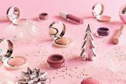 Makeup products on pink background. Christmas or New Year party makeup cosmetics. Blushes, eyeshadow and lip gloss