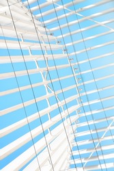 Geometric abstraction with a lot of white and black parallel curved lines, wide and thin on a blue background. Vertical photo