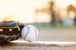 Copy space on blurred background by baseball with glove, laying on sports field.
