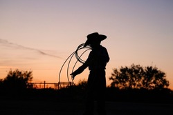 Young cowboy with rope in Texas sunset on ranch for childhood western lifestyle.
