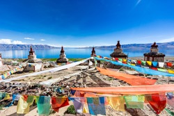 White tibetan stupa with 5 color flags at in Tibet, China
