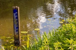 Water level depth meter, gauge or staff gauge, in the river. Extreme low water in river. Global warming. Shortage or lack of water due to hot temperatures. Government measurements. Crisis and climate.