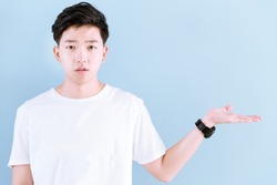 Young Asian casual teenage boy indicate blank space on blue background.