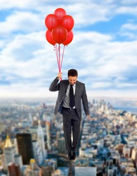 Businessman flying high with helium balloons.