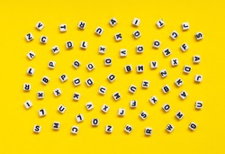 White cubes with letters scattered randomly on a yellow background. The Image can be used for many purposes, book covers or concepts relating to grammar and typography.
