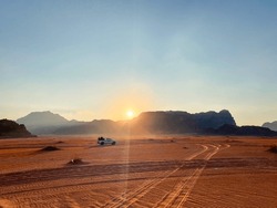 Safari in Wadi Rum desert, Jordan, Middle East. Tourists in the car ride on off-road on sand among the beautiful rocks at sunset.