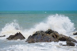 White ocean waves crashing over coastal sea rocks in summer.Thailand