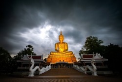 Beautiful  Big Golden Buddha statue against night sky in Thailand temple,khueang nai District, Ubon Ratchathani province, Thailand.Amazing Buddha image with evening dark sky clouds with movement.