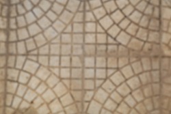 Tiles laid out in a circles, cross in the center, beige monochromatic blurred background.