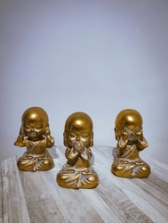 A vertical view of Three small Japanese Buddhist figures representing the three wise monkeys san saru (三猿). dont see, dont hear and dont listen to evil