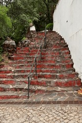 Staircase with stone steps, red-painted cement, and a central iron handrail. Access to the Church of São João, Sanctuary of Nossa Senhora da Piedade, Lousã, Portugal.