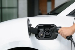Progressive concept of hand insert an emission-free power connector to the battery of electric vehicle at home. Electric vehicle charging via cable from charging station to EV car battery