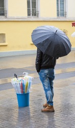 Man stood in rain on street selling umbrellas
