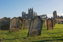 Remains of an ancient english abbey ruins with gothic architecture in rural countryside landscape and cemetary