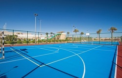 Outdoor clay multi purpose sports pitch with blue surface and nets at tropical hotel holiday resort