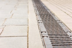 Metal drainage grid on cobblestone