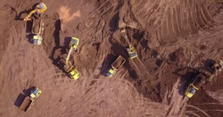 Aerial: Vast excavation site with multiple heavy industry vehicles.
