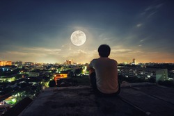 A man stand alone watch the full Moon night in the Bangkok city, Thailand.