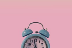 Alarm clock over pink. Time concept. Blue alarm clock morning time. Blue alarm clock with copy space.Blue alarm clock with copy space on a pink background.