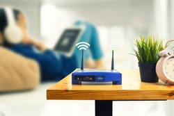 closeup of a wireless router and a man using smartphone on living room at home ofiice