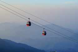 Two red cable cars decending from a station on a mountain in Genting Highland, Pahang, Malaysia