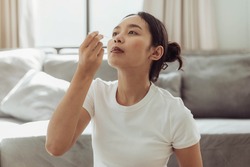 Young woman self test for COVID-19 at home with a nasal swab. asian woman using coronavirus covid-19 rapid antigen home testing kit, Coronavirus nasal swab test for infection.