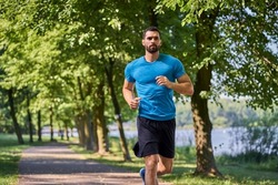 Young male athlete practices running in a park