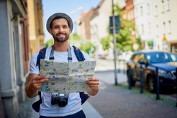 Male tourist with map in visiting European city in summer.Young man exlporing city