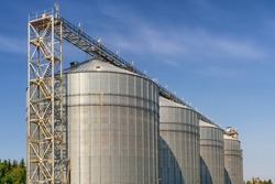Large metal elevator tanks against a bright blue sky. Silo or granary at sunny day
