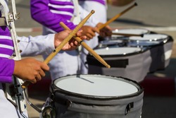 purple shirt musician in marching band playing drum with drumstick on band background