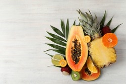 Exotic fruits on white wooden background, space for text.