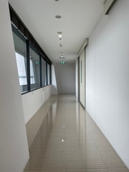Hall way in a building white color with green fire exit sign