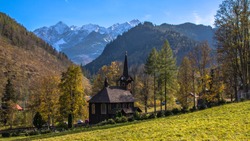 Romantic wooden church in Tatranská Javorina, Slovakia, with panoramic view of Tatra Mountains, early autumn